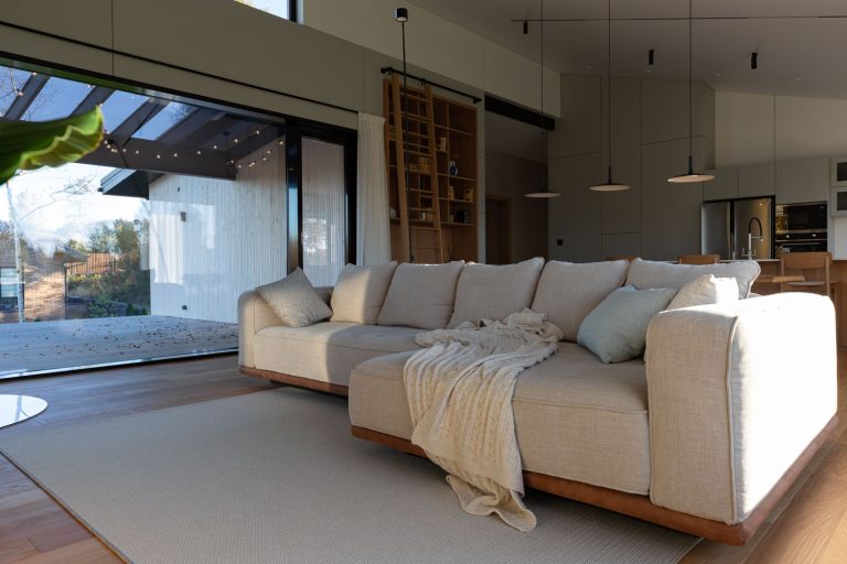 Уютная диванная зона с панорамными окнами в теплых оттенках.
